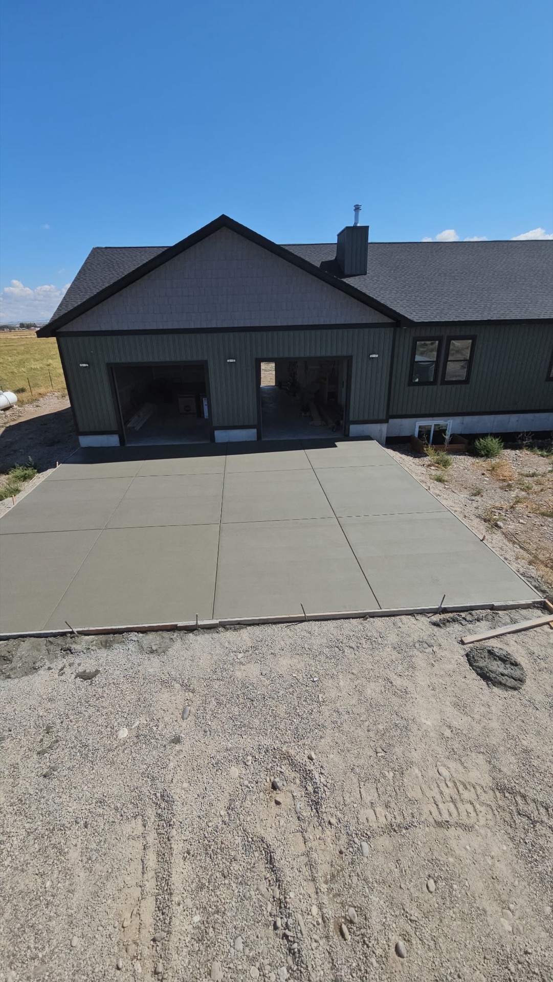 Newly poured concrete driveway leading to an attached garage at a new home in Eastern Idaho by Skinner Customs