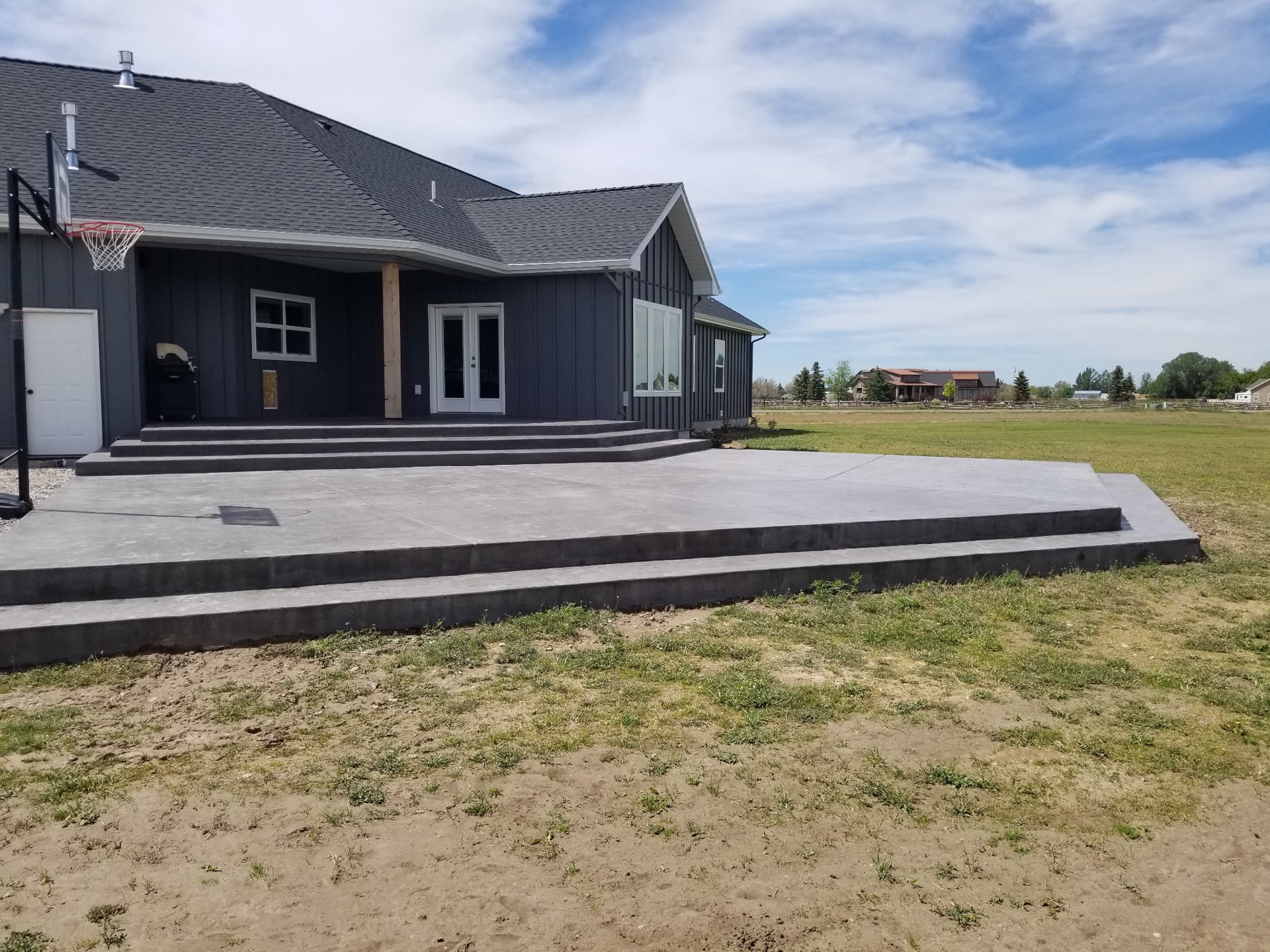 Grey concrete patio and steps at a rural Eastern Idaho home — exterior flatwork poured by Skinner Customs