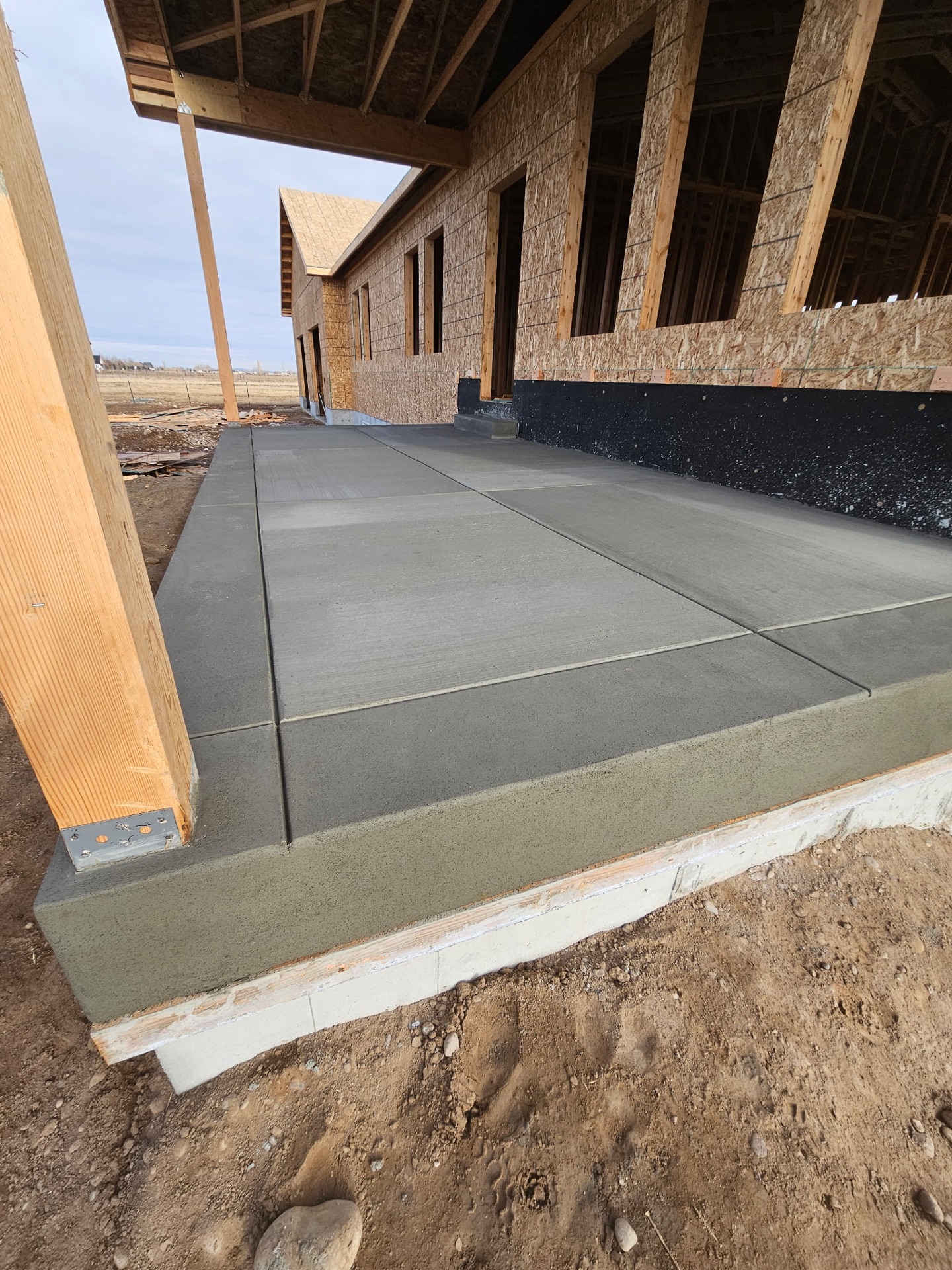Fresh grey concrete porch slab at a framed new-construction home in Eastern Idaho by Skinner Customs